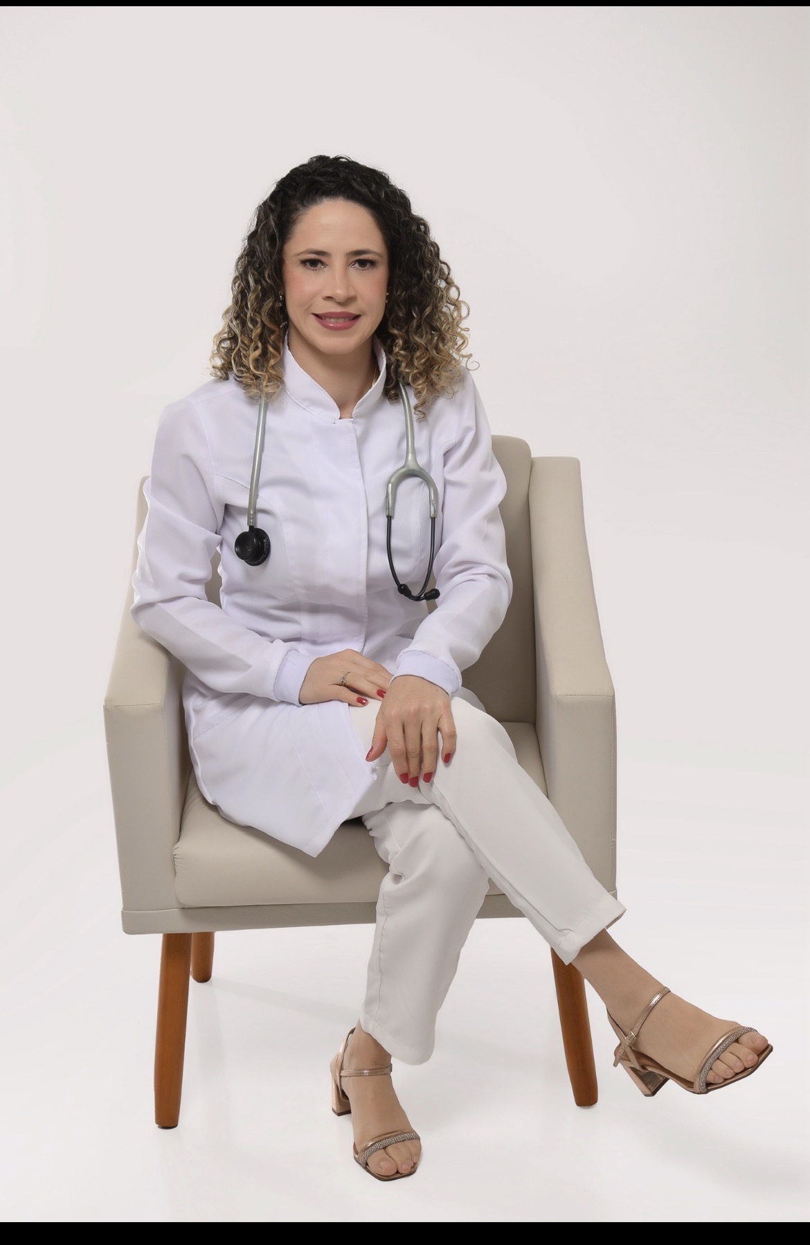 Elisângela Lima, fisioterapeuta especialista em atendimento domiciliar, sentada com jaleco branco e estetoscópio